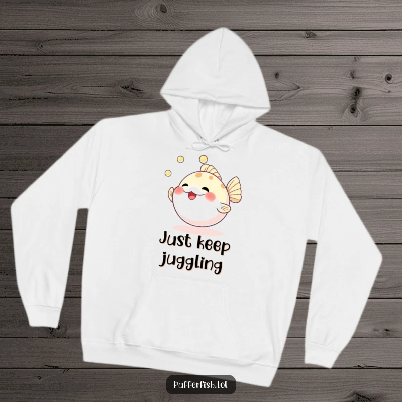 Funny hoodie depicting a beaming pufferfish skillfully juggling three lustrous pearls, perfect for cozy, humorous wear.