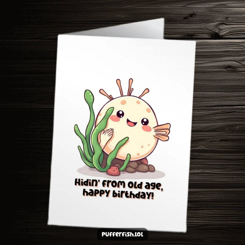 Funny Free Printable Birthday Card: A cute kawaii pufferfish playfully hiding behind a green sea plant, ready to surprise.